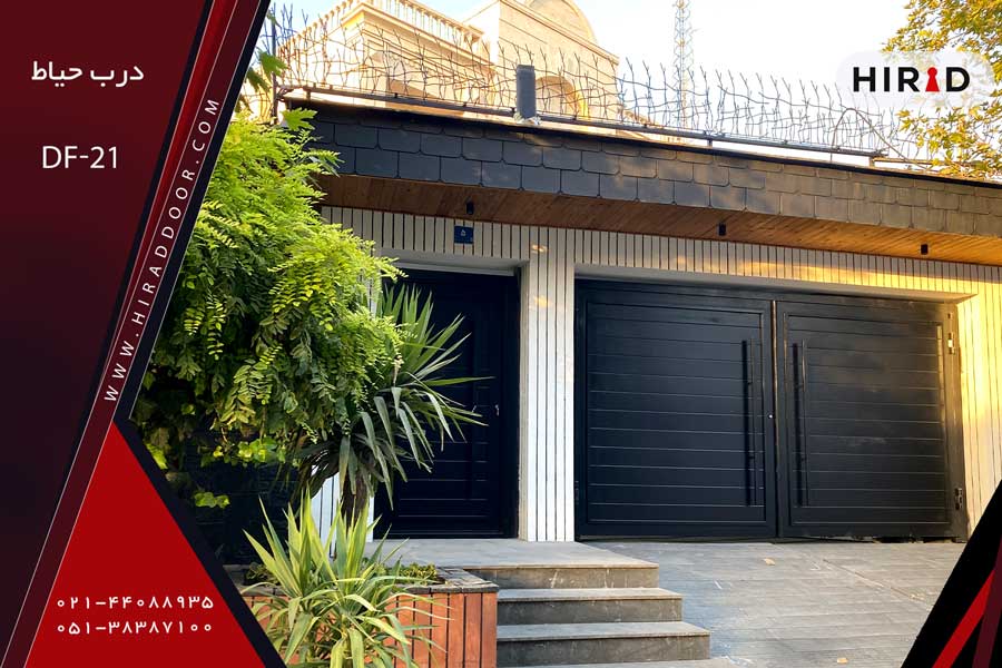 درب حیاط و درب پارکینگ بزرگ، مشکی رنگ، یکپارچه فلزی، با دستگیره های عمودی بلند، نصب شده در ساختمان ویلایی بزرگ